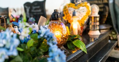 Artificial and real flowers and lit candles lying on the tombstone in the cemetery.