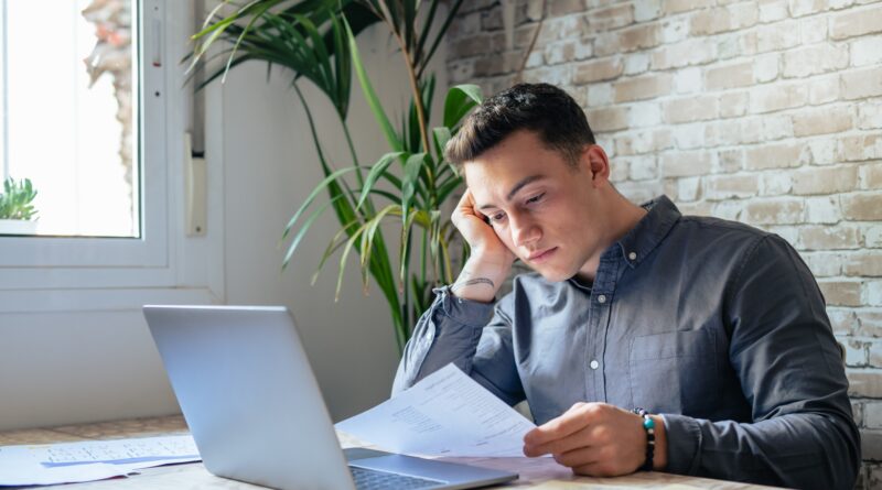 Confused frustrated young man reading letter, debt notification, bad financial report