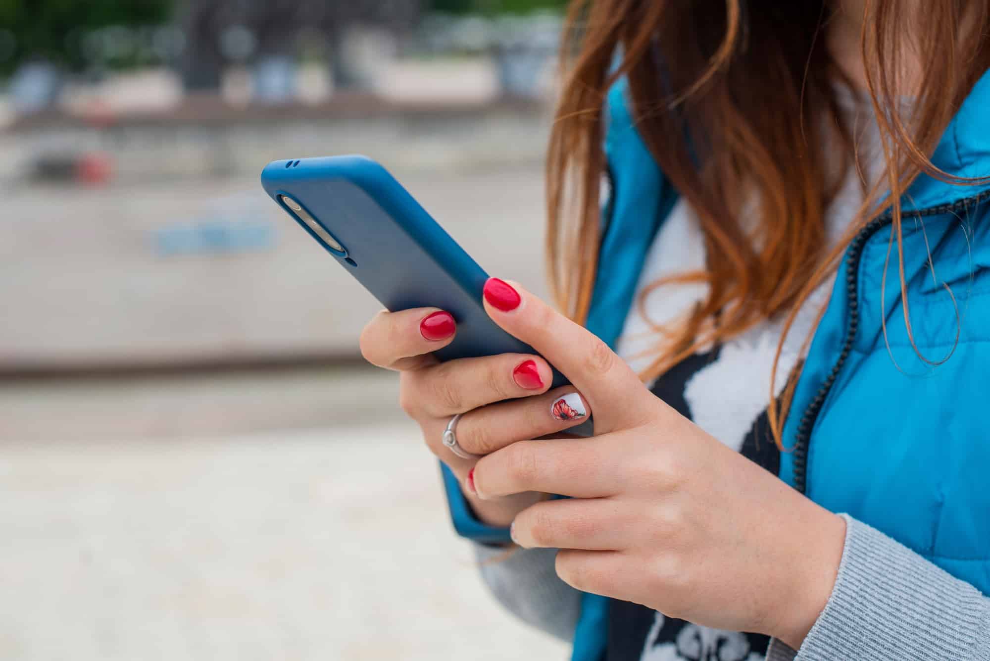 girl writes sms text in the device phone in her hands