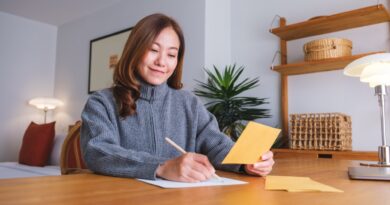 Portrait image of a young woman writing on a letter and envelopes
