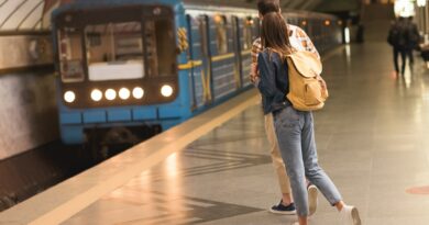 rear view of stylish couple of travelers with backpacks at metro station